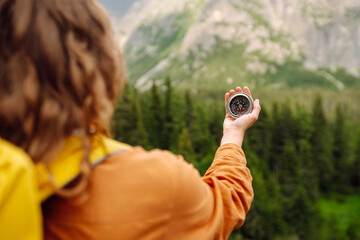 
Wanderlust concept. Stylish woman holding a compass in her hand while traveling in the mountains. The concept of hiking, nature.