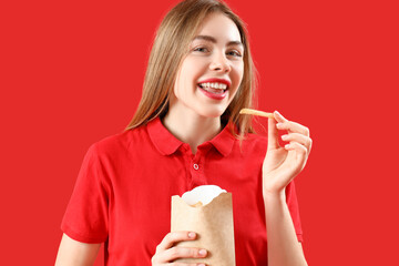 Canvas Print - Beautiful happy young woman with pack of french fries on red background