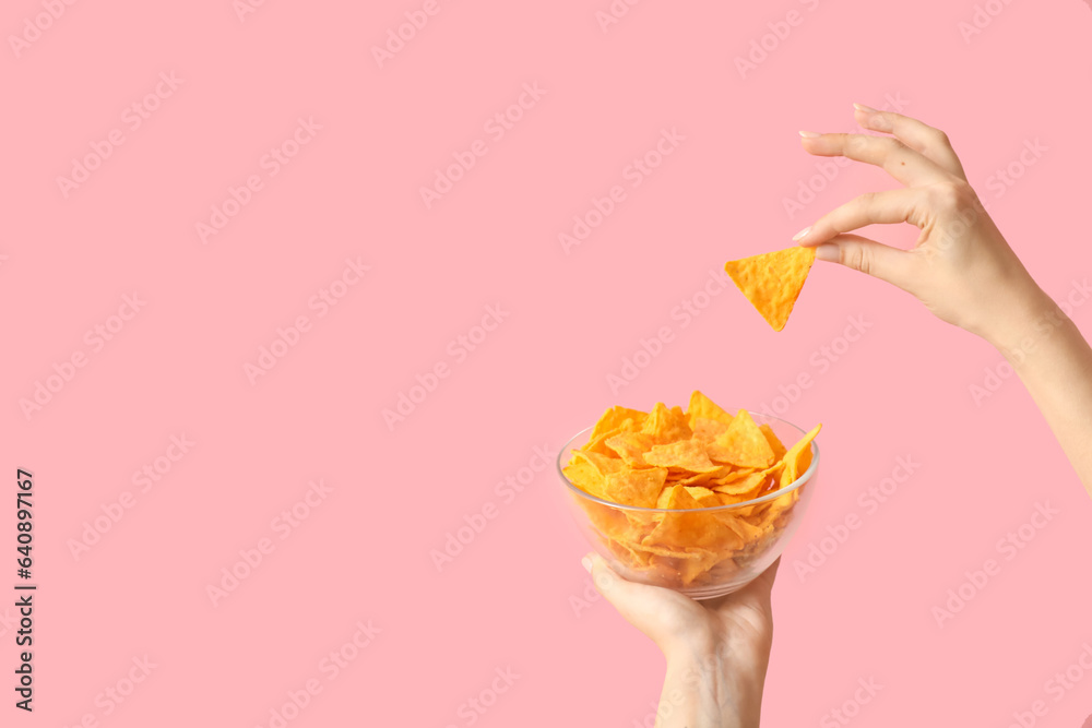 Female hands holding nachos on pink background