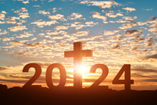 Silhouette Of Christian Cross With 2024 Years At Sunset Background. Concept Of Christians New Year 2024