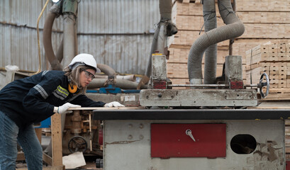 Female carpenter working with CNC machine in wood workshop. Female joiner wearing safety uniform processing plank wooden with CNC machine in wooden warehouse storage