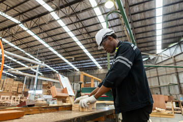 Man American African wearing safety uniform and hard hat working on wood sanding electric machines at workshop manufacturing wooden. Male carpenter worker wood warehouse industry.