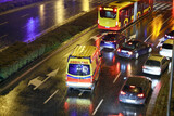Fototapeta Miasto - Karetka medyczna ratunkowa w deszczu na sygnale jedzie  na sygnale jedzie wieczorem z pomocą