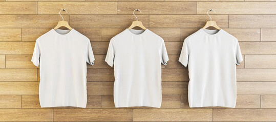 Wall Mural - Three empty white t-shirts hanging on wooden wall background. Ad, textile and fashion concept. 3D Rendering.
