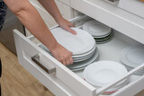 Fototapeta  - Wyjmować talerze obiadowe z szuflady w kuchni