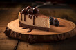 Slice of triple chocolate cheesecake served on a wooden plate
