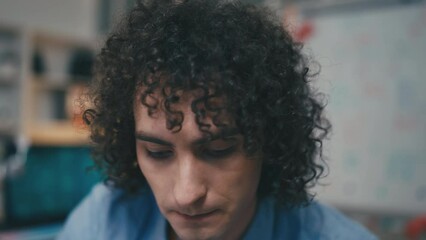 Young curly-haired man working as programmer in office, computer screen pov, job