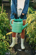 © standret - Plastic watering can in hands. Beautiful young woman is gardening