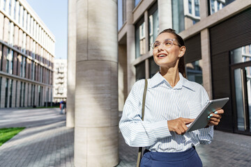 Creative manager is a smart young woman in office clothes. A person uses a tablet to surf the Internet.  Online responds to the client's email message.