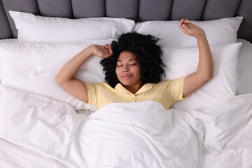 Poster - Beautiful young woman stretching in soft bed, above view