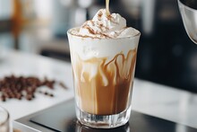 Glass With Warm Coffee Drink With Pumpkin Spice Or Cinnamon, Whipped Milk Foam And Chocolate In A White Sunlit Modern Kitchen Interior