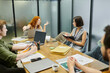 © LIGHTFIELD STUDIOS - redhead businesswoman pointing with finger near colleagues, meeting room, laptops, documents, graphs