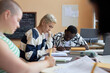 © AnnaStills - Focus on two young intercultural students carrying out examination test while sitting next to each other and writing down answers in copybooks