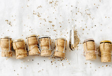 Top View New Year, Xmas Concept, Row Wine Corks From Sparkling Wine And Christmas Bauble Champagne Glass With Shiny Golden Sequins On White Fur, Copy Space, Food Still Life Aesthetic, Holidays