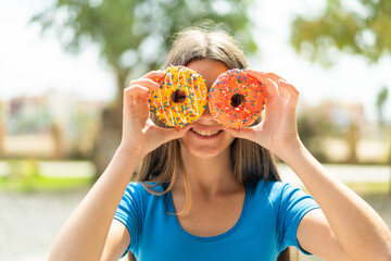 Poster - Teenager girl at outdoors holding donuts in eyes