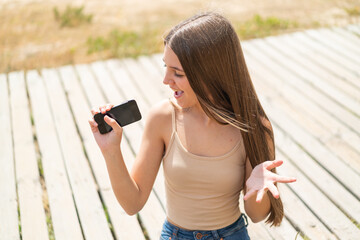 Sticker - Teenager girl at outdoors using mobile phone and singing