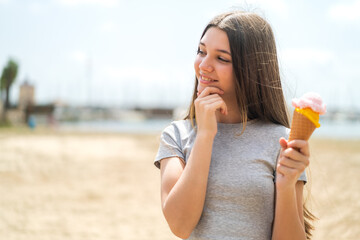 Wall Mural - Teenager girl with a cornet ice cream at outdoors thinking an idea and looking side