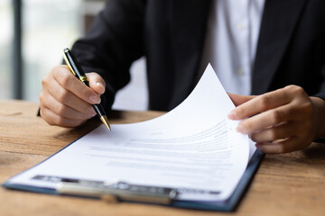 Lawyer working on paperwork in the office. Female lawyer reading contract agreement documents before signing legally.