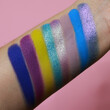 Eye shadow swatches, dry powder, set of blue, purple  matte multichrome metallic brush strokes on skin. Cosmetic makeup texture samples, smear trace samples on pink background. Realistic photography