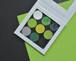 Green eye shadow palette with matte and glitter colors in a white palette on green and black background