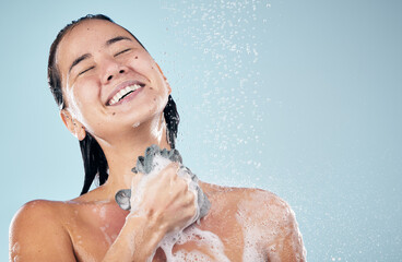 Canvas Print - Skincare, shower and woman smile with loofah in studio isolated on a blue background. Water splash, hygiene and model happy, washing and cleaning to bath in wellness, healthy body and mockup space