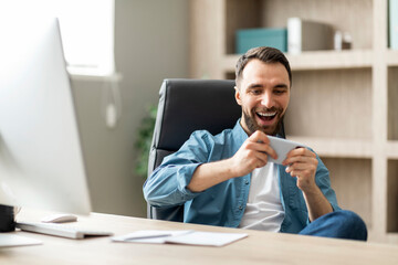 Aufkleber - Office Leisure. Cheerful Male Manager Playing Video Games On Smartphone At Workplace