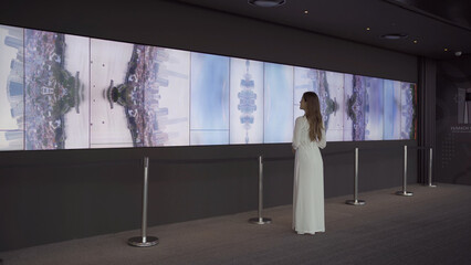 Portrait of Asian Vietnamese woman with dress at Sky bar looking at TV screen in museum, urban city, Vietnam. People lifestyle.