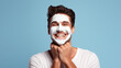 Happy young man using a beauty cream on his face to keep it healthy and fresh