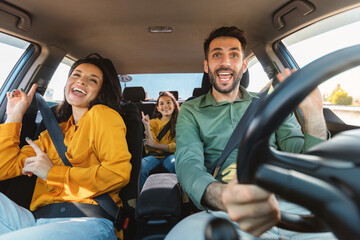 We are going on vacation. Happy family of three driving in their automobile, dancing to music and singing