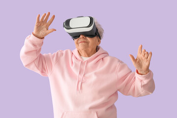 Wall Mural - Senior woman in VR glasses on lilac background