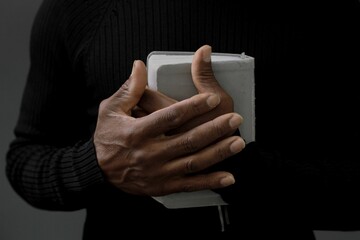 man praying with bible with black background with people stock image stock photo	