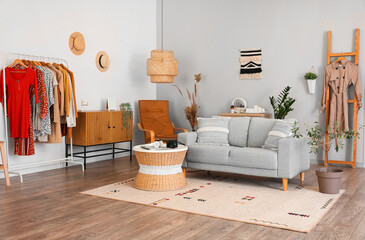 Wall Mural - Interior of light living room with grey sofa, table and clothes