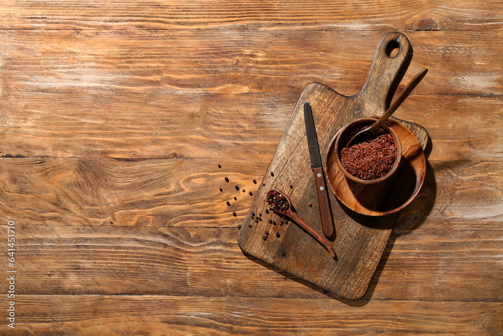 New cutting board and bowl with brown rice on wooden background