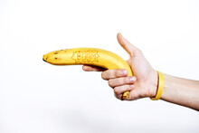 Conceptual Shot Of Human Hand With Yellow Rubber Bracelet Holding Banana With Inscription ‘Boom’ Isolated On White Background  