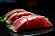 A close-up of a slice of tuna sashimi accompanied by wasabi and soy sauce, captured in a macro shot