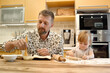 © Clique Images - Adult bearded man and little charming girl at table in kitchen making sweet pastries to bake