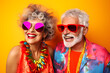 studio portrait of happy mature retired couple wearing colourful sunglasses enjoying retirement