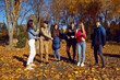 © Studio Romantic - Joint activity in the form of games of happy young people in park on sunny, clear day, holding hands against the background of autumn forest. Cheerful smiling friends are enjoying autumn walk in park.