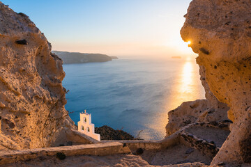 Wall Mural - Church of Agios Nikolaos in Santorini island, Greece. View of the sea and rocks at sunset.