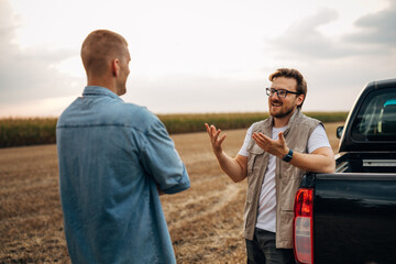 Two Caucasian farmers are standing in the field and talking.