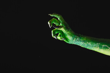 Wall Mural - Green monster hand with black nails reaching on grey background