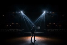 A Man Standing In Front Of A Stage With Three Spotlights