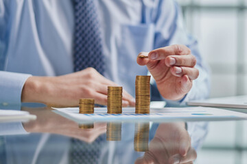 Wall Mural - Businessman stacking coins on table, business growth concept. Hand puts coin to stack.