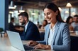 © Premreuthai - Cheerful businesspeople using a laptop in an office. Two happy young entrepreneurs smiling while working together in a modern workspace. Two young businesspeople sitting together at a table.