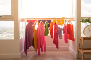 Colorful clothes hanging on the balcony dry in sun at apartment.