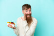 Redhead man with long beard holding a bowl of fruit isolated on blue background whispering something