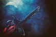 © Dimid - A maniac with a chainsaw in his hand close up on a dark background with smoke.