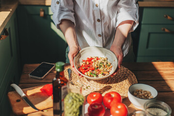 Wall Mural - Young woman eating healthy food sitting in the beautiful interior with green flowers on the background