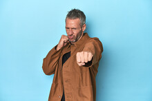 Middle-aged Caucasian Man On Blue Backdrop Throwing A Punch, Anger, Fighting Due To An Argument, Boxing.