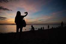 Silhouette Of A Woman On The Beach At Sunrise In Vietnam Taking Photo Or Selfie